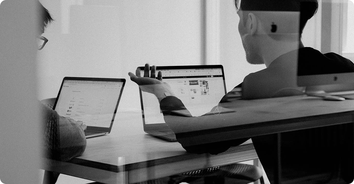 Two people discussing marketing work across laptops at a table