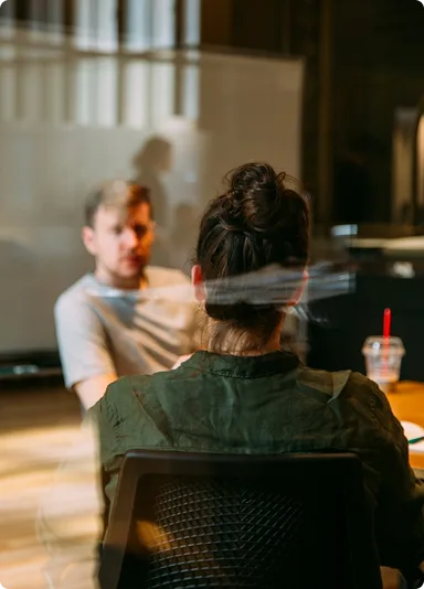 Two people in conversation across a table in a bright meeting room