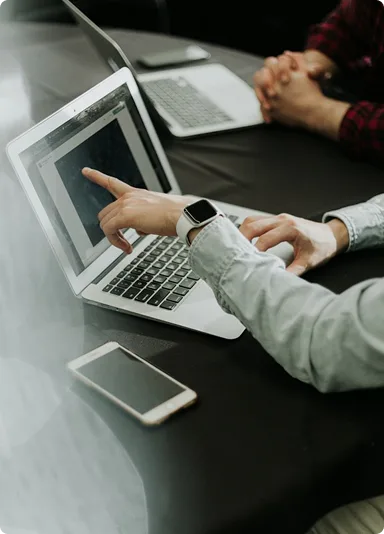 Hands pointing at a laptop screen next to a phone during a working session